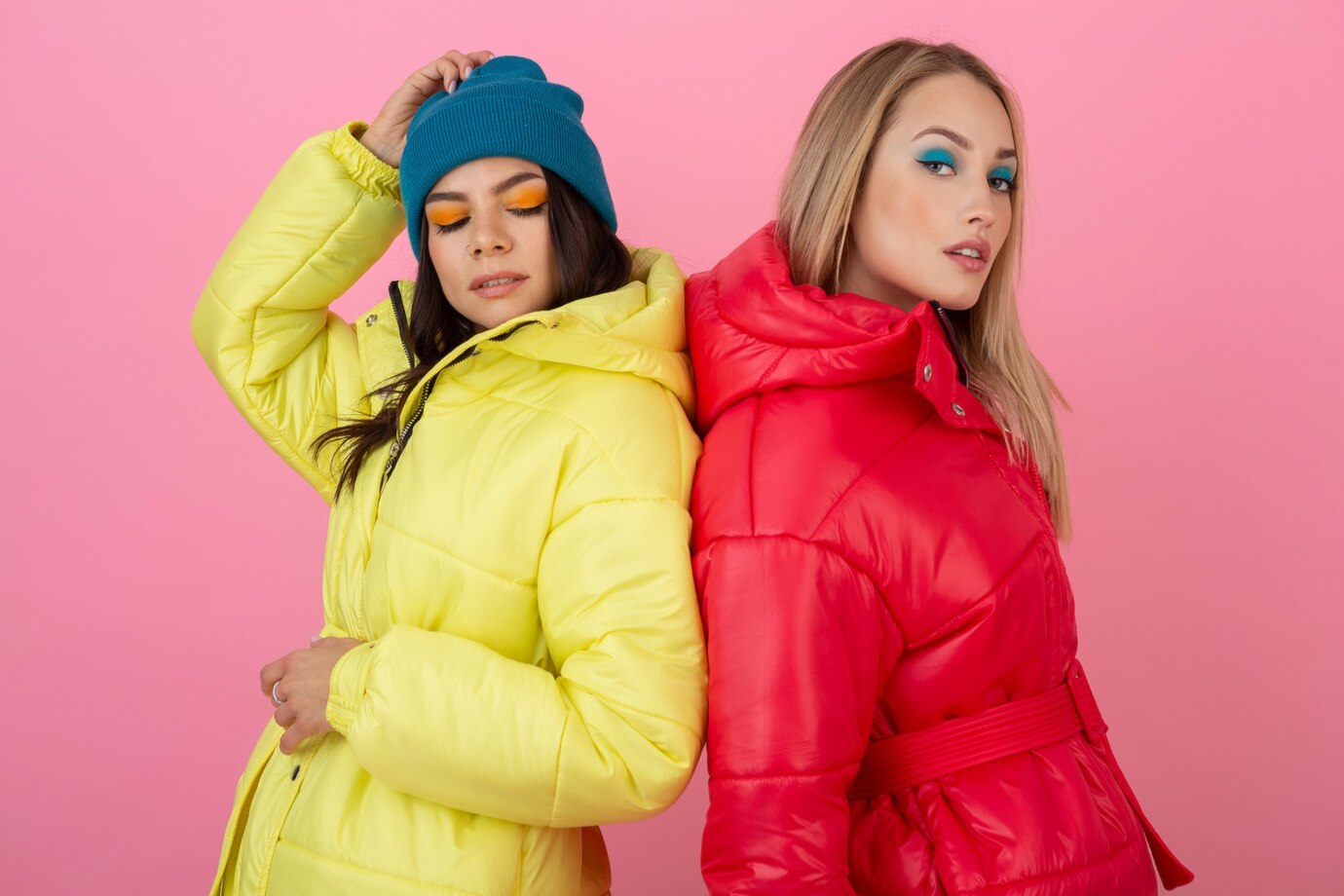 two-attractive-girls-posing-pink-background-colorful-winter-down-jacket-bright-red-yellow-color_285396-7204